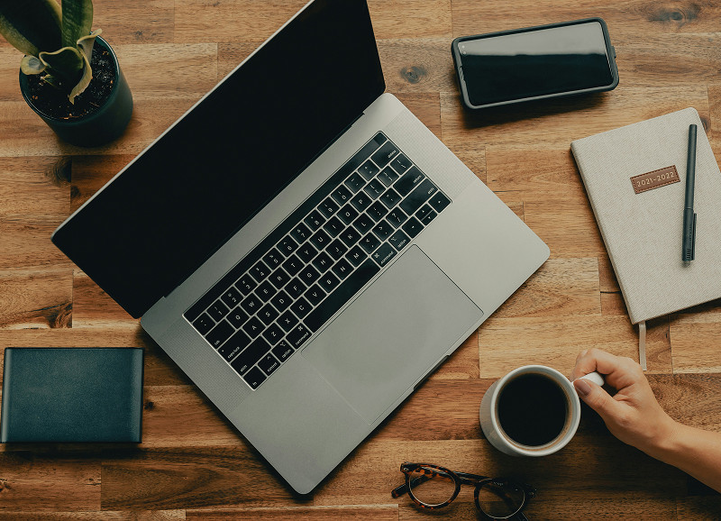 computer, telefoon, 2 notitie boekjes op een bureau